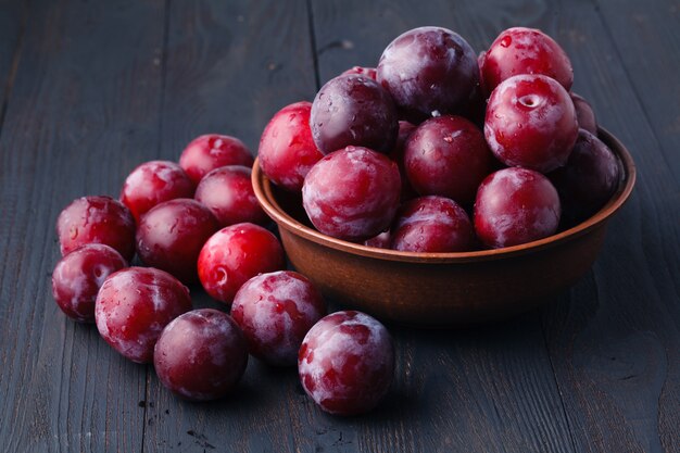 Plums in dish on dark wooden table