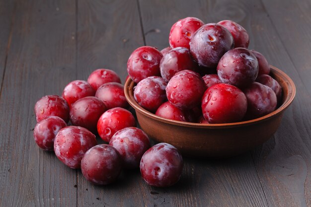 Plums in dish on dark wooden table