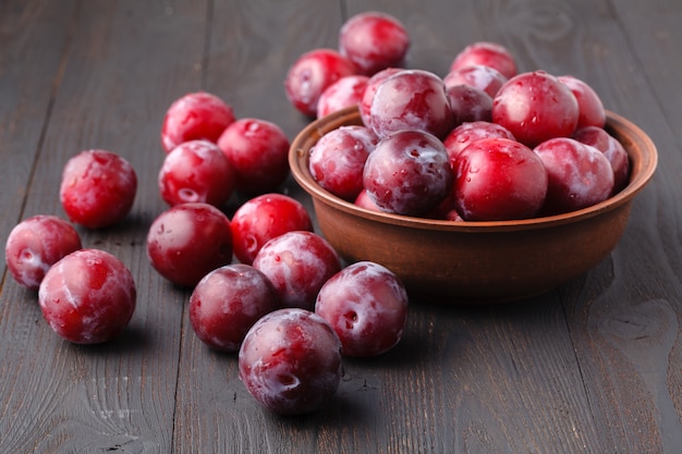 Plums in dish on dark wooden table