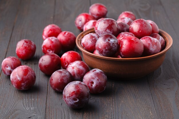 Plums in dish on dark wooden table