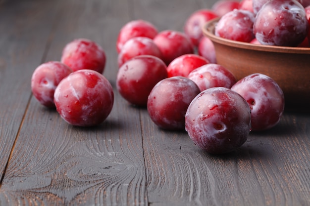 Plums in dish on dark wooden table