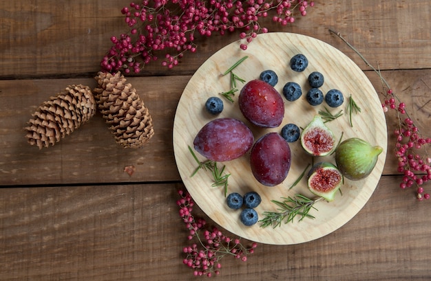 Plums, figs and blueberries on wooden plate