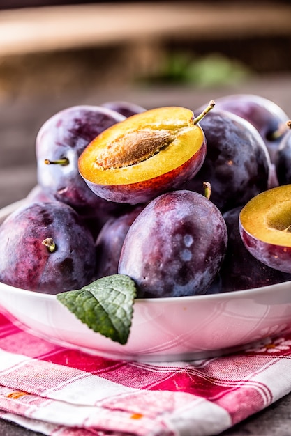 Plums. Fresh juicy plums in a bowl on a wooden or concrete board.