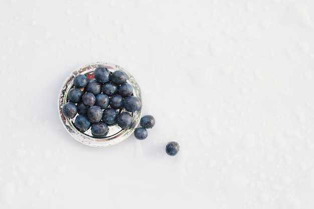 Plums in an iron bowl on the table after rain. Flat lay