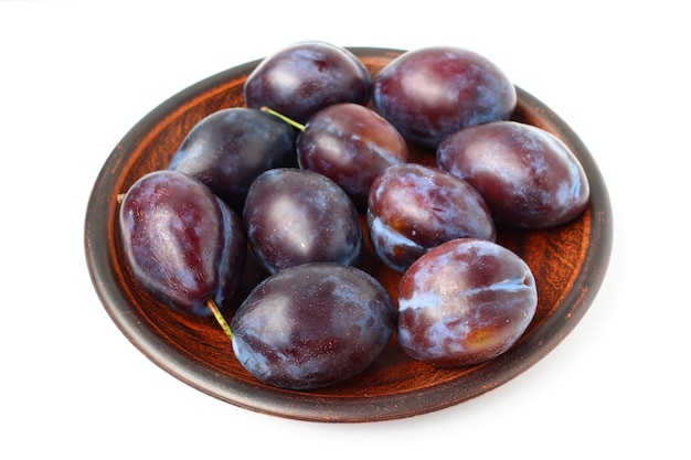 Plums in a plate on a white surface