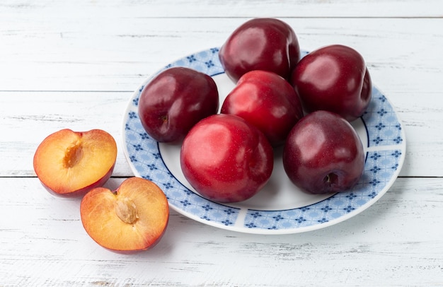 Plums in a plate over wooden table.