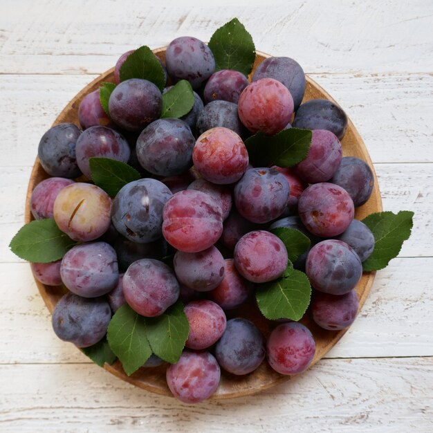 plums in a round dish on light