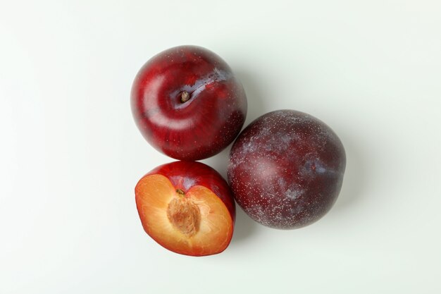 Plums with a half on a white background.