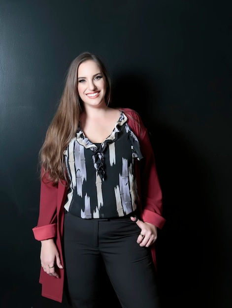 Plus size attractive lady posing and standing against dark backdrop with a whiten perfect smile Beautiful smiling brunette big size woman with brown long hair Perfect makeup fashion beauty portrait