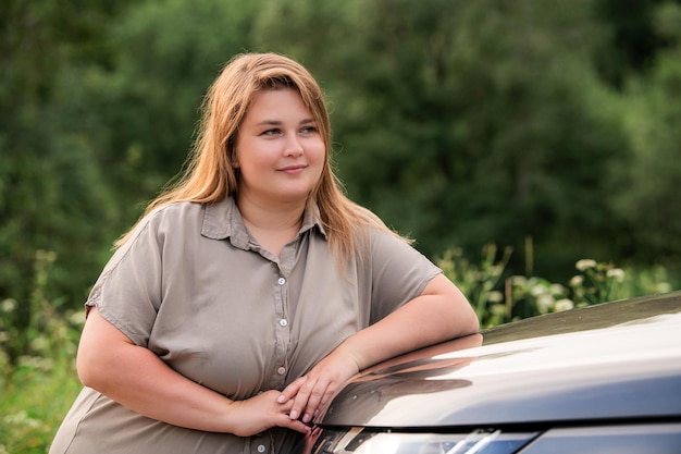 Plus size beautiful girl posing for portrait on background of nature in summer Plus size model stands with a positive attitude