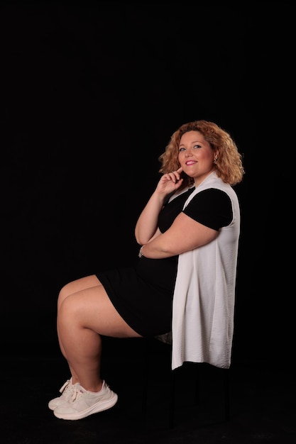 Foto donna bionda di taglia plus in uno studio fotografico su sfondo nero donna curva