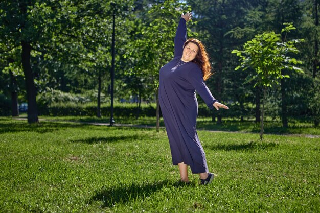 Plus size lichaam zwaarlijvige vrouw dansen op grasveld in park