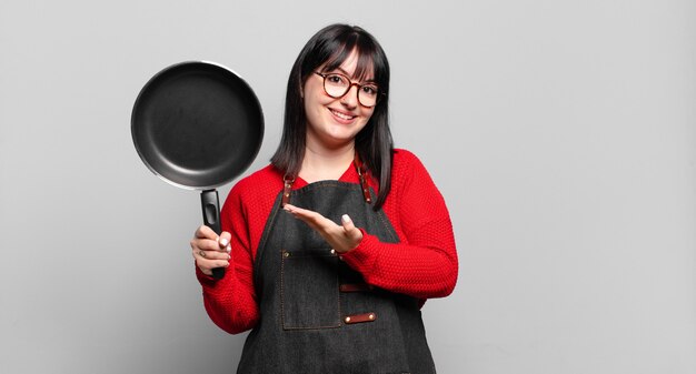 Plus size mooie vrouw die vrolijk lacht, zich gelukkig voelt en een concept toont in kopieerruimte met palm van hand