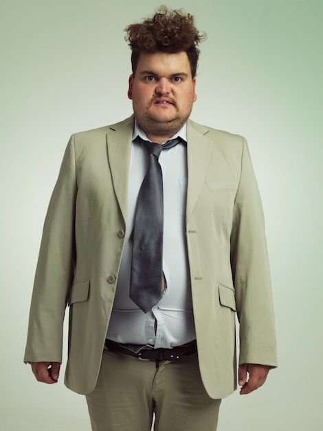 plus size portrait and man with stomach shirt and professional annoyed with clothes for work adult male person and guy with moody unhappy and upset with fitting of belly in suit in studio job