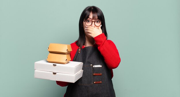 Taglie forti donna graziosa che copre la bocca con le mani con un'espressione scioccata e sorpresa, mantenendo un segreto o dicendo oops