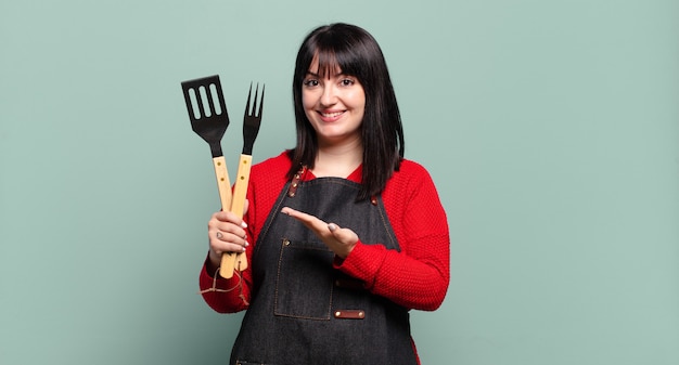 Plus size bella donna sorridente allegramente, sentendosi felice e mostrando un concetto nello spazio della copia con il palmo della mano