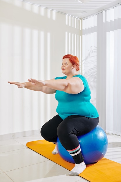Plus size vrouw balanceren op fitness bal