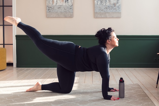 plus size vrouw doet pilates yoga stretching oefening thuis