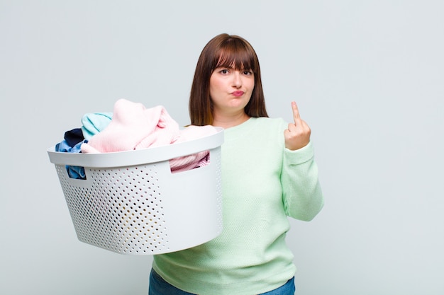 Plus size woman feeling angry, annoyed, rebellious and aggressive, flipping the middle finger, fighting back