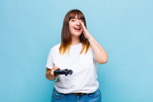 Plus size woman feeling happy, excited and positive, giving a big shout out with hands next to mouth, calling out