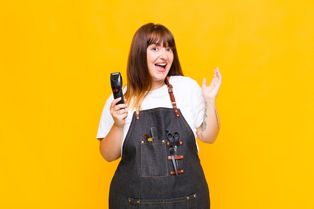 Plus size woman feeling happy, excited, surprised or shocked, smiling and astonished at something unbelievable