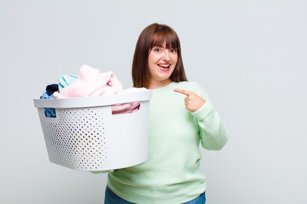 Plus size woman looking excited and surprised pointing to the side and upwards to copy space