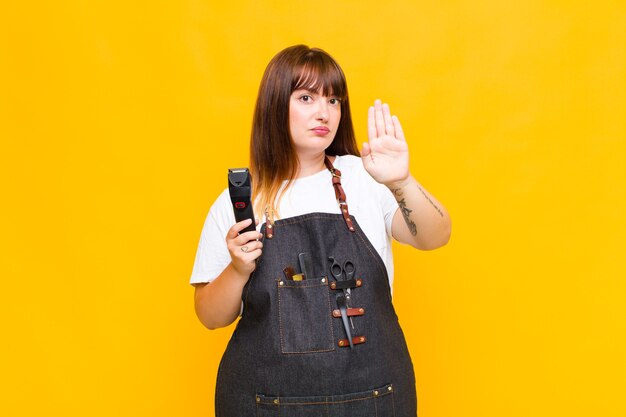 Plus size woman looking serious, stern, displeased and angry showing open palm making stop gesture