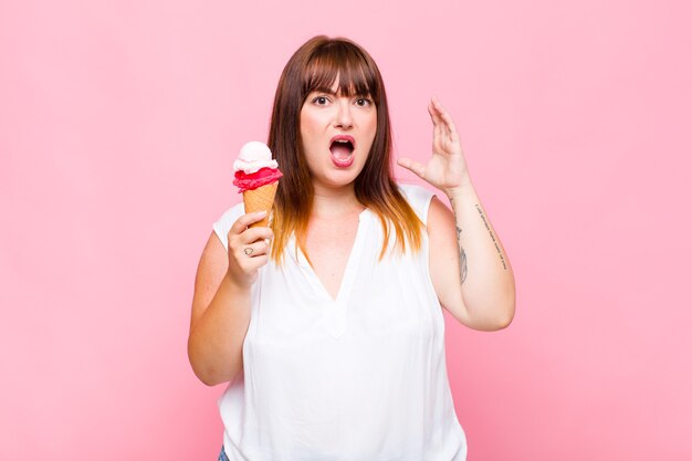 Plus size woman screaming with hands up in the air, feeling furious, frustrated, stressed and upset