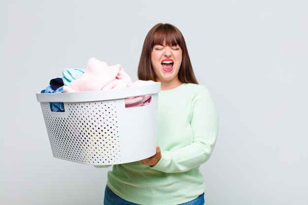 Plus size woman shouting aggressively, looking very angry, frustrated, outraged or annoyed, screaming no