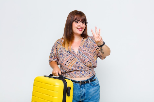 Plus size woman smiling and looking friendly, showing number two or second with hand forward, counting down