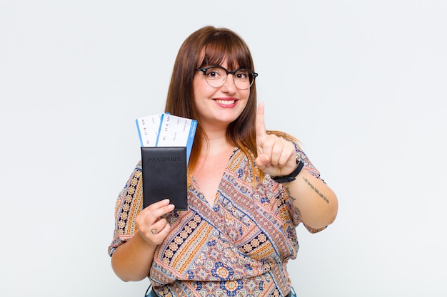 Plus size woman smiling proudly and confidently making number one pose triumphantly, feeling like a leader