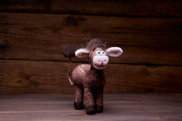 Plush bull toy on a wooden background. A soft toy greets the viewer. Symbol of 2021 New Year.