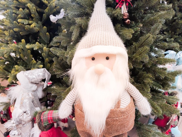 Gli gnomi di natale di peluche con la barba bianca stanno nell'atrio del centro commerciale sotto l'albero di natale