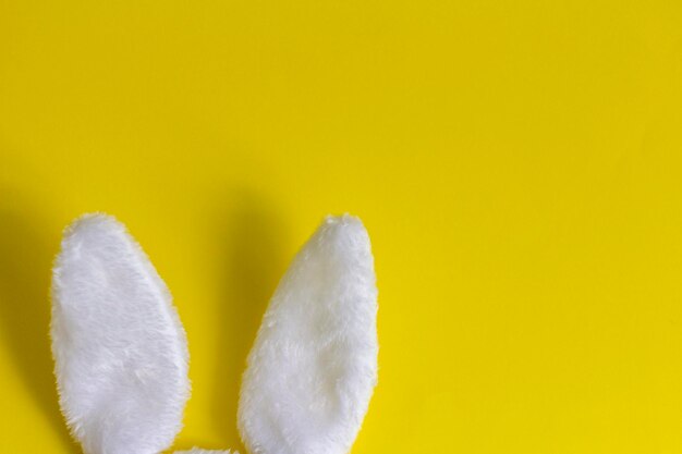 Foto orecchie di coniglio di peluche su sfondo giallo concetto di pasqua con un posto da copiare