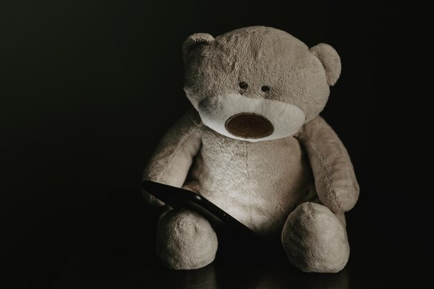 Plush teddy bear with smartphone in bedroom Kid's smartphone addcition concept