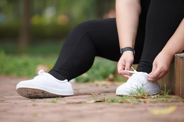 아침에 공원에서 달리기 위해 신발 끈을 묶는 Plussize 젊은 여성