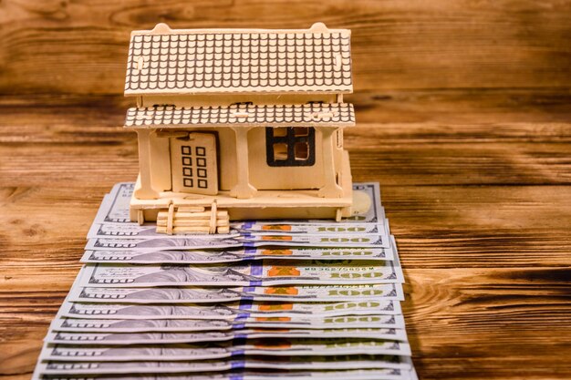 Plywood model of the house and one hundred dollar banknotes. Loan, real estate concept