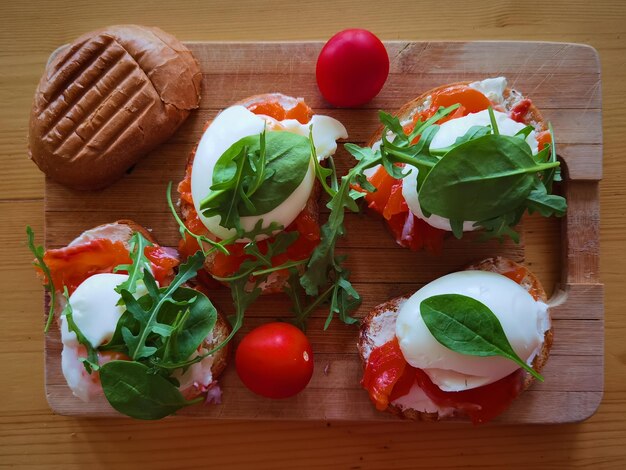 Poached egg on grilled toast with smoked salmon rucola and\
vegetables on white board healthy breakfast