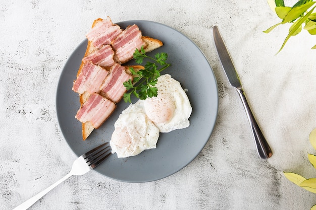 Poached eggs with bacon on sourdough toast. isolated on white marble background. Homemade food. Tasty breakfast. Selective focus. Hotizontal photo.