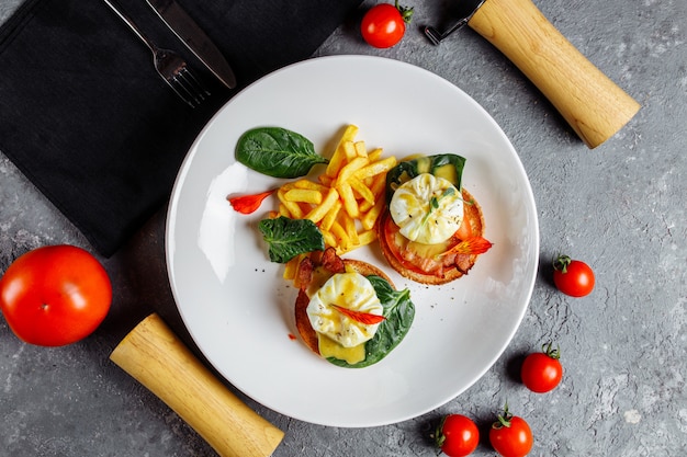 Poached eggs with french fries and bacon on toast