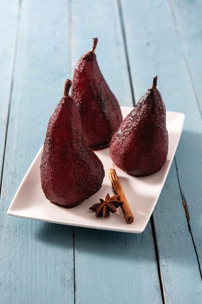 Poached pears in red wine on blue wooden table.