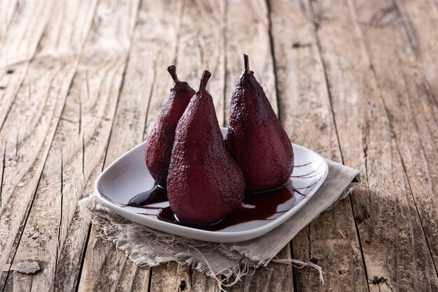 Poached pears in red wine on wooden table