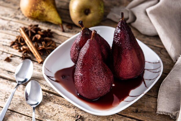 Poached pears in red wine on wooden table