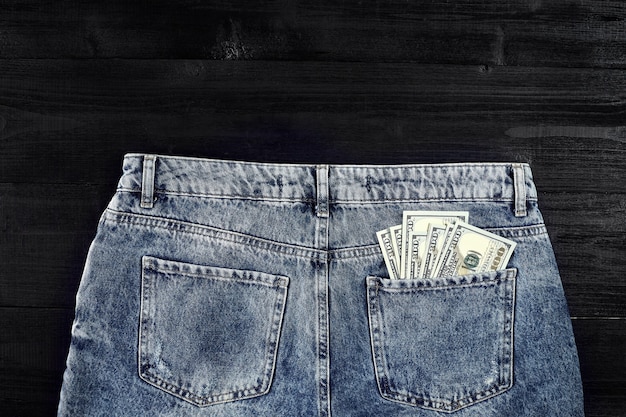 Pocket money dollar in hip pocket of worn blue jeans closeup