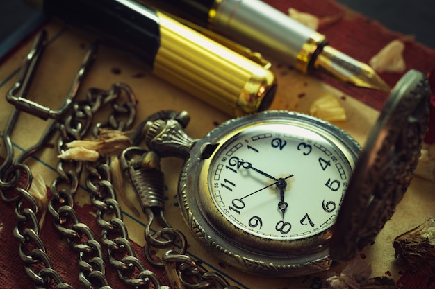 Pocket watch and pen on table.