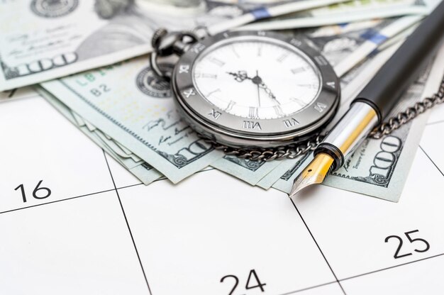 Pocket watch with pen and money on calendar Business concept