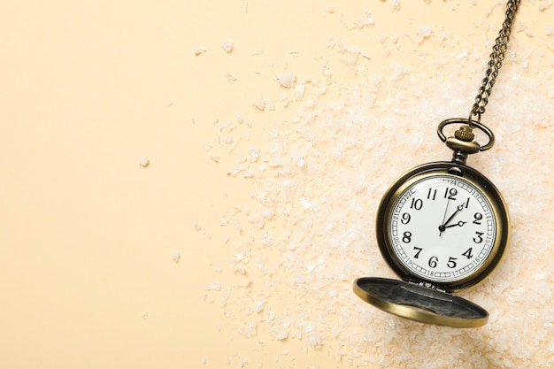 Pocket watch with snow on a light background