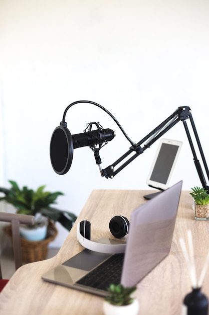 Photo podcast and blogging concept - modern workplace with laptop and microphone at radio station office