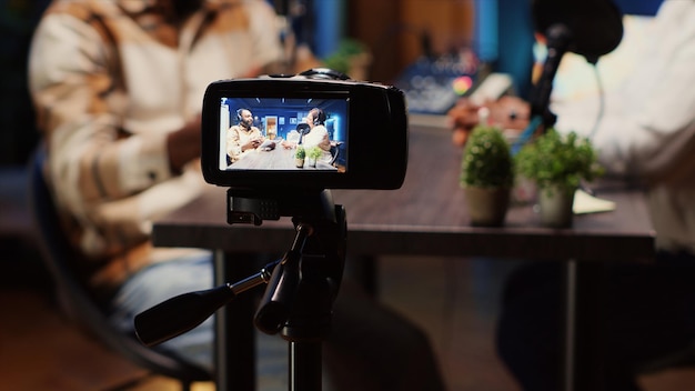 Podcast host using smartphone on tripod to record guest telling interesting story