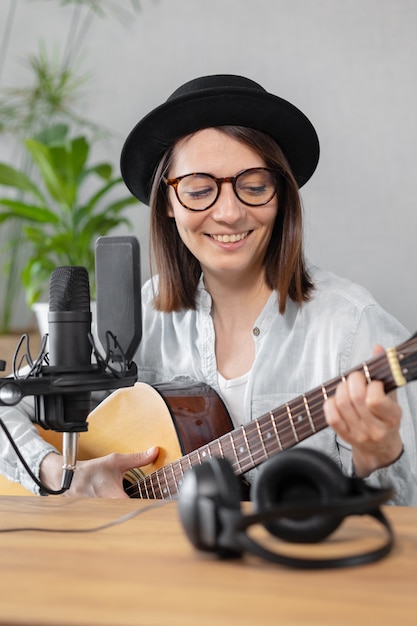 Podcast muziek audio content creatie mooie Europese vrouw podcaster in een hoed met een gitaar of